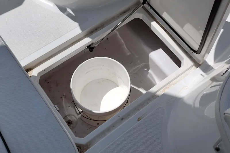 Slide: The Image of Open storage compartment with a white bucket on a 2024 Wellcraft 223 Fisherman boat. - 30