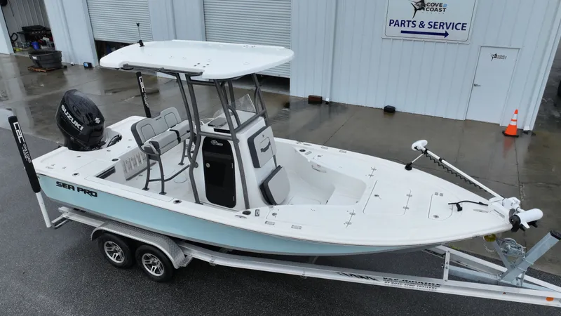 Slide: The Image of A 2025 Sea Pro 230 DLX boat on a trailer in front of a workshop. - 1