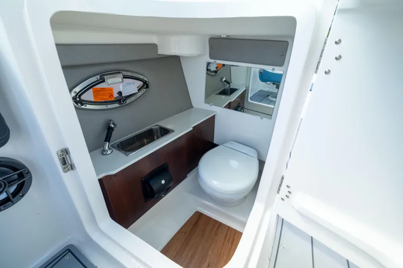 Slide: The Image of 2026 Chaparral 250 OSX boat interior bathroom with sink, toilet, and mirror. - 13