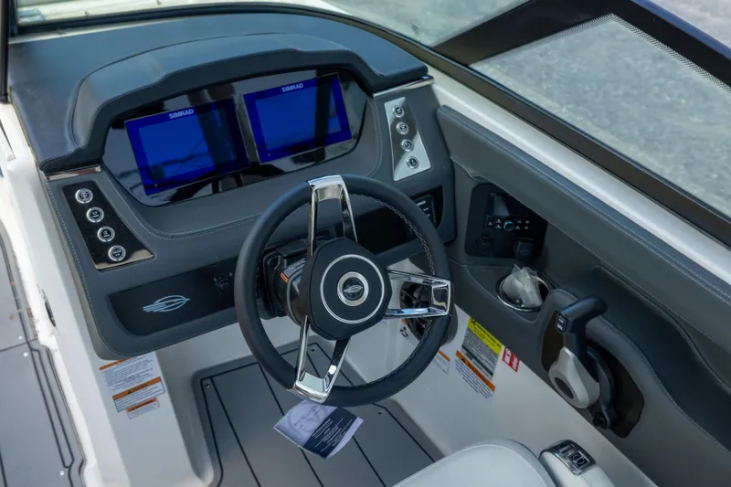 Slide: The Image of 2026 Chaparral 250 OSX boat dashboard with dual Simrad displays and modern steering wheel. - 11