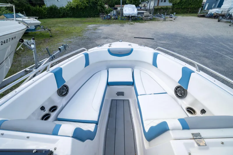Slide: The Image of 2026 Chaparral 250 OSX boat interior with white and blue seating, docked outdoors. - 5