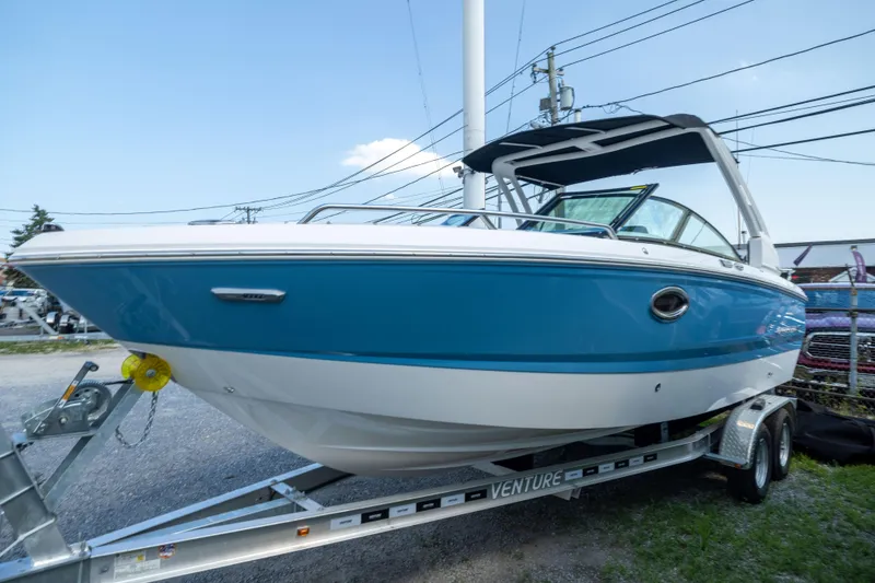 Slide: The Image of 2026 Chaparral 250 OSX boat on trailer, blue and white design, outdoor display. - 4
