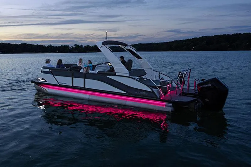 Slide: The Image of Manufacturer Provided Image: Manufacturer Provided Image: 2025 Harris Grand Mariner 250 pontoon boat with pink LED lights on a lake at dusk. - 4