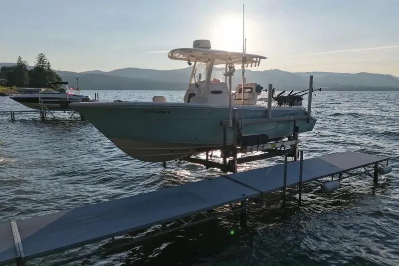 Slide: The Image of 2020 Cobia 240 Center Console boat docked on a serene lake at sunset. - 4