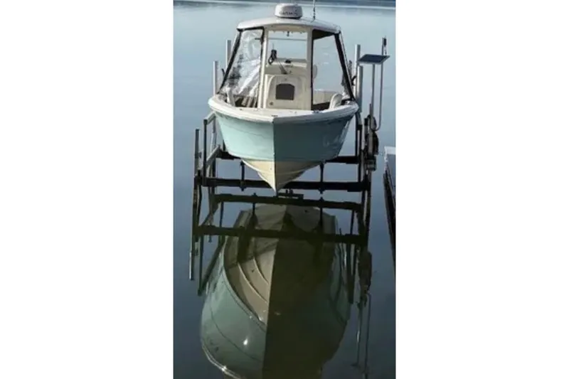 The Image of 2020 Cobia 240 Center Console boat on lift, reflecting on calm water. - 13