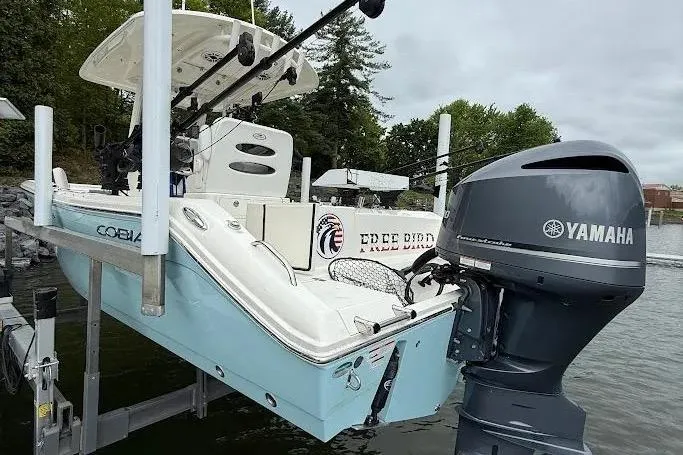 Slide: The Image of 2020 Cobia 240 Center Console boat with Yamaha engine on a lift by the water. - 7