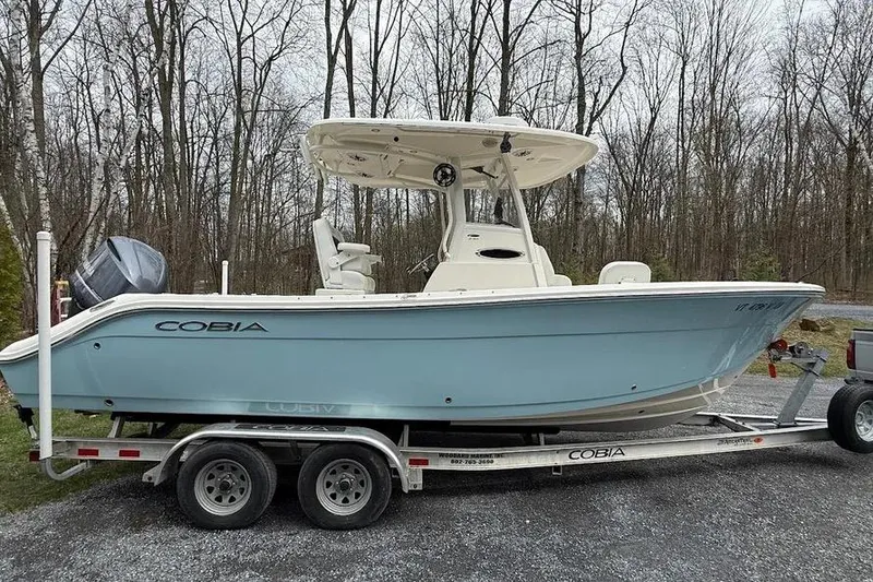 Slide: The Image of 2020 Cobia 240 Center Console boat on trailer, parked in wooded area. - 14
