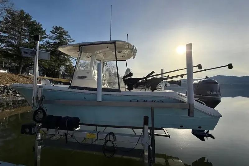 Slide: The Image of 2020 Cobia 240 Center Console boat on lift at sunrise by the water. - 17