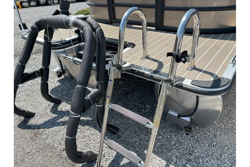 Slide: The Image of A metal swim ladder is attached to a pontoon boat, resting on a gravel surface. - 23