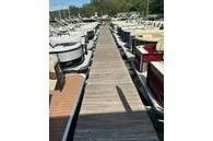 Slide: The Image of A wooden dock leads between several parked pontoon boats. - 26