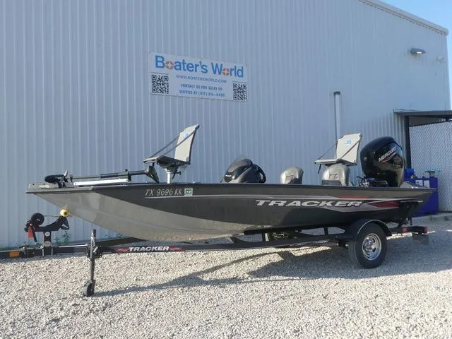 The Image of A gray Tracker boat, model Pro Team 175 TF, is on a trailer in front of a building. - 1