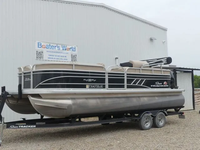 The Image of A 2020 Sun Tracker Party Barge 22 DLX on a trailer in front of a building. - 1