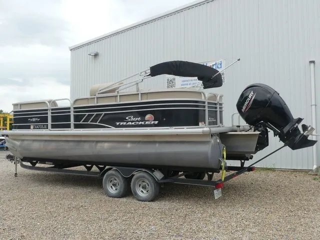 Slide: The Image of A 2020 Sun Tracker Party Barge 22 DLX on a trailer in front of a building. - 6