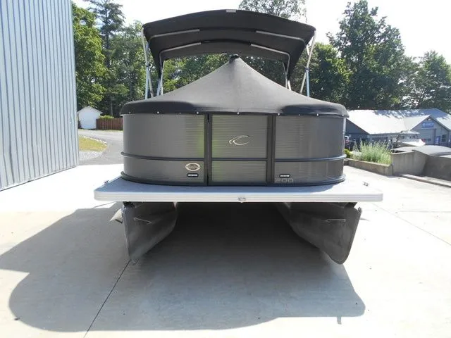 Slide: The Image of A 2024 Crest Classic LX 200 L pontoon boat on concrete, surrounded by trees. - 6