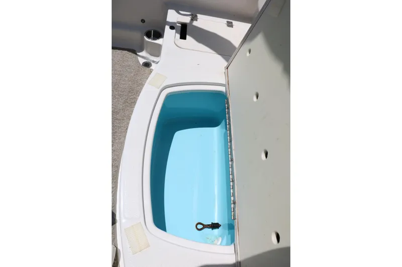 Slide: The Image of Open storage compartment on 2013 Chaparral 19 Sport H2O boat, featuring a blue interior. - 27