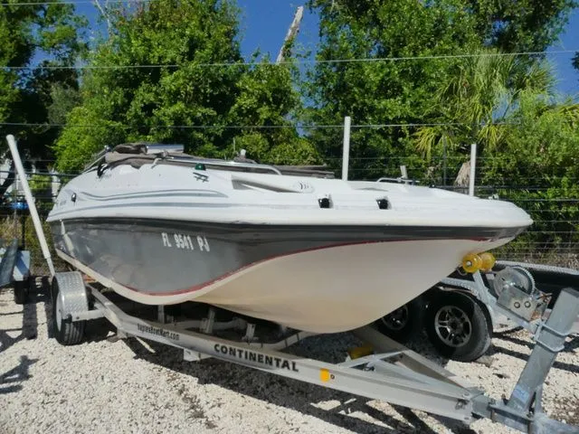 The Image of A 2012 Hurricane Sundeck 188 boat on a trailer, surrounded by trees. - 1