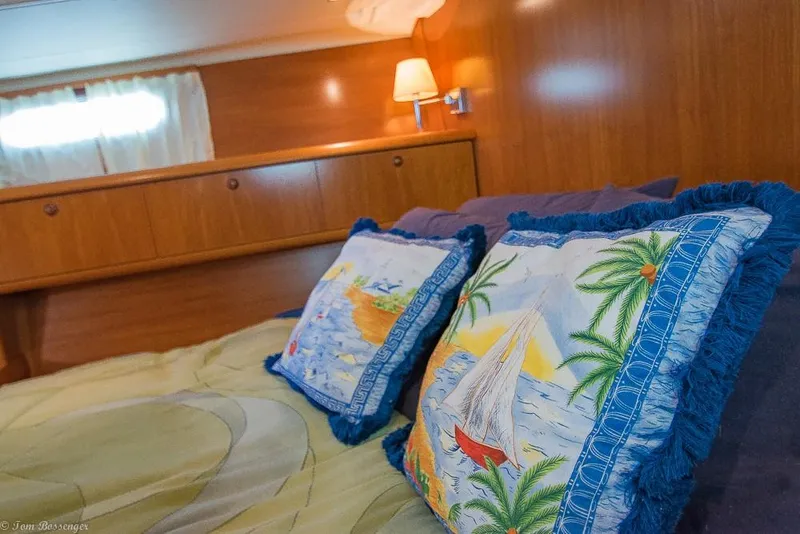 Slide: The Image of The image shows a cozy bedroom with wooden walls and colorful pillows featuring sailboat designs. - 20
