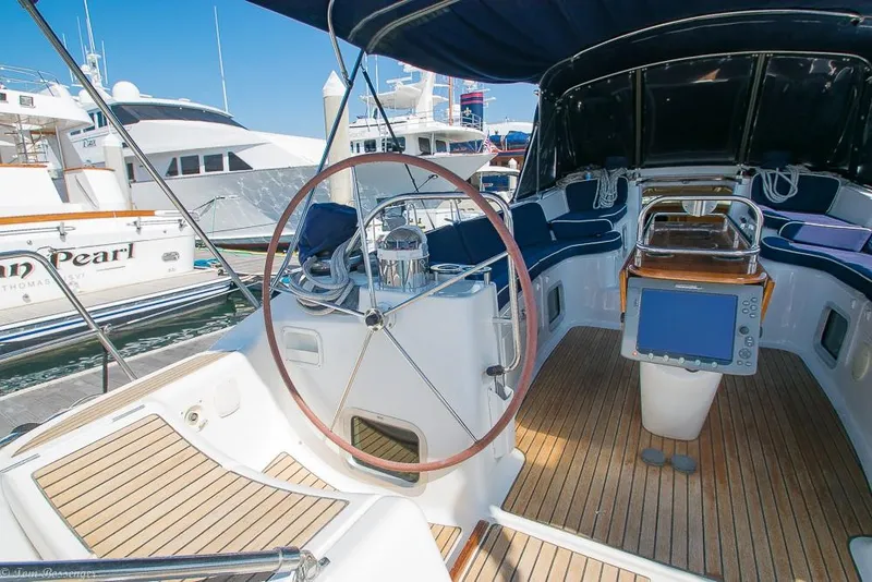 Slide: The Image of The cockpit of a 2006 Jeanneau Sun Odyssey 54 DS with a large steering wheel and wooden deck. - 42