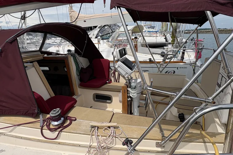 Slide: The Image of 1990 Island Packet 27 sailboat cockpit with maroon canopy and seating, docked at marina. - 1