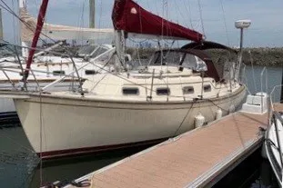 Slide: The Image of 1990 Island Packet 27 sailboat docked at marina with red sails. - 62