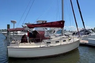 Slide: The Image of 1990 Island Packet 27 sailboat docked at marina under clear blue sky. - 61