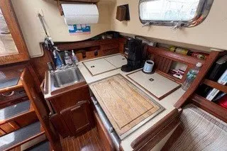 Slide: The Image of 1990 Island Packet 27 sailboat galley with sink, stove, and wooden cabinetry. - 22