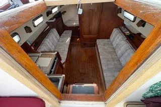 Slide: The Image of Interior view of a 1990 Island Packet 27 sailboat, featuring cozy seating and wooden finishes. - 5