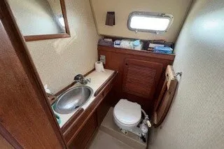 Slide: The Image of 1990 Island Packet 27 sailboat bathroom with sink, toilet, and wooden cabinetry. - 32