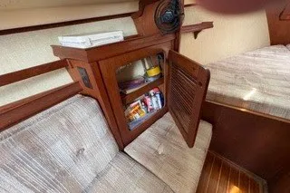 Slide: The Image of Interior of 1990 Island Packet 27 sailboat with open wooden cabinet and cushioned seating. - 34