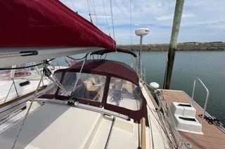 Slide: The Image of 1990 Island Packet 27 sailboat docked, featuring maroon canopy and clear skies. - 11