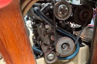 Slide: The Image of Engine compartment of a 1990 Island Packet 27 sailboat, showcasing mechanical components and belts. - 45