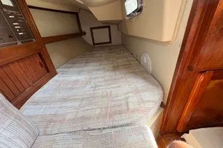 Slide: The Image of 1990 Island Packet 27 sailboat interior cabin with cozy sleeping area and wooden accents. - 21