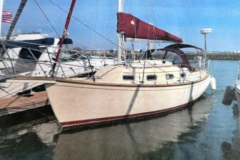 The Image of 1990 Island Packet 27 sailboat docked in a marina under clear blue skies. - 0