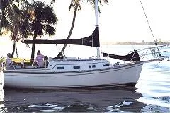 Slide: The Image of 1990 Island Packet 27 sailboat docked near palm trees on a sunny day. - 1