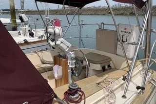 Slide: The Image of 1990 Island Packet 27 sailboat cockpit with steering wheel and canopy in marina. - 2