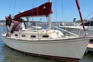 Slide: The Image of 1990 Island Packet 27 sailboat docked, featuring maroon sails and a cream hull. - 57