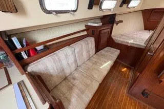 Slide: The Image of Interior of 1990 Island Packet 27 sailboat with wooden flooring and cushioned seating. - 26