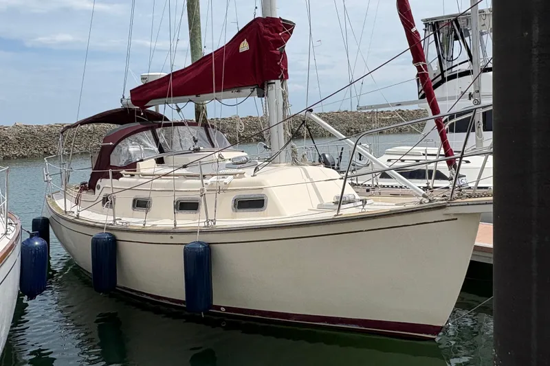The Image of 1990 Island Packet 27 sailboat docked with maroon sails and fenders. - 0