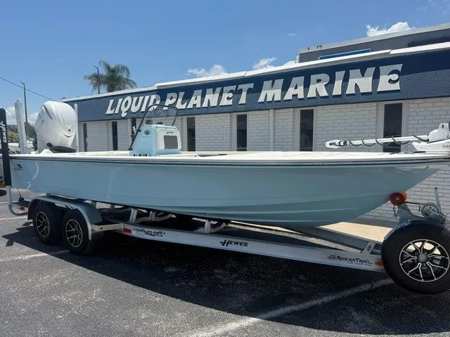 Slide: The Image of A 2027 Hewes Redfisher 21 boat on a trailer in front of a building labeled "Liquid Planet Marine." - 2