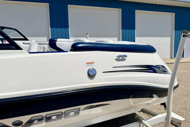 Slide: The Image of 2004 Bombardier SEADOO Utopia 185 boat, white with blue accents, parked near blue building. - 48
