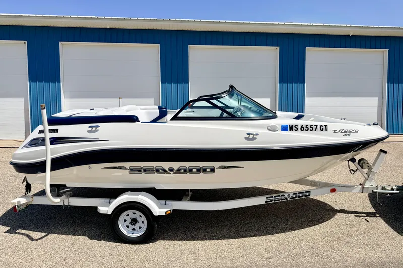 Slide: The Image of 2004 Bombardier SEADOO Utopia 185 boat on trailer, parked near blue building. - 4