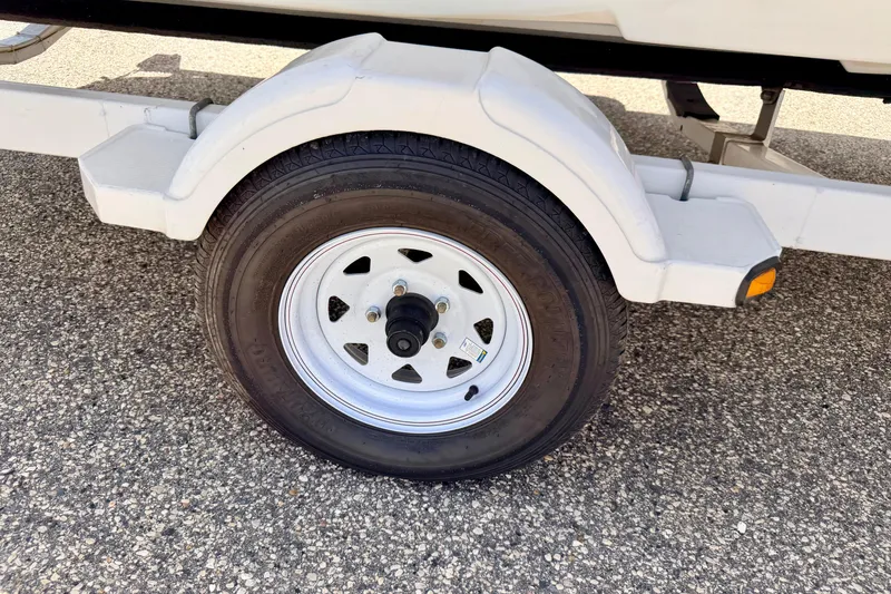 Slide: The Image of Trailer wheel of a 2004 Bombardier SEADOO Utopia 185 on asphalt surface. - 56