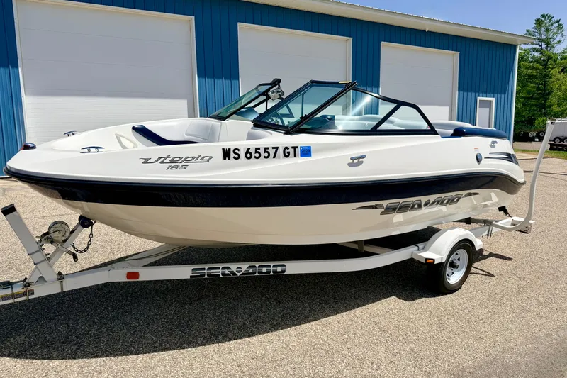 Slide: The Image of 2004 Bombardier SEADOO Utopia 185 boat on trailer, parked outside blue building. - 3