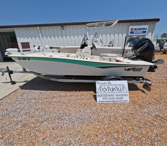 The Image of A 2023 Mako Pro Skiff 15 CC boat on a trailer in front of a building. - 1