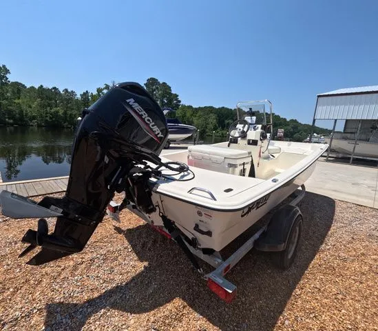 Slide: The Image of A 2023 Mako Pro Skiff 15 CC boat on a trailer beside a calm river. - 6