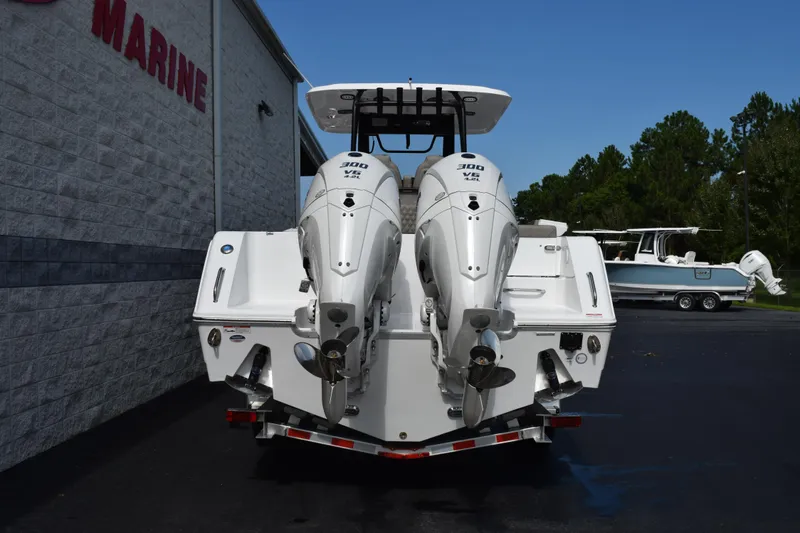 Slide: The Image of 2027 Sea Hunt Gamefish 28 boat with dual 300 V6 engines, parked outside a marine shop. - 5
