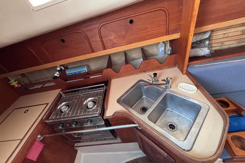 Slide: The Image of 1989 CAL 33 yacht kitchen with dual sinks, stove, and wooden cabinetry. - 15