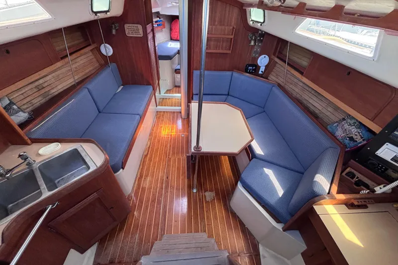 Slide: The Image of Interior of 1989 CAL 33 sailboat with blue seating and wooden flooring. - 9
