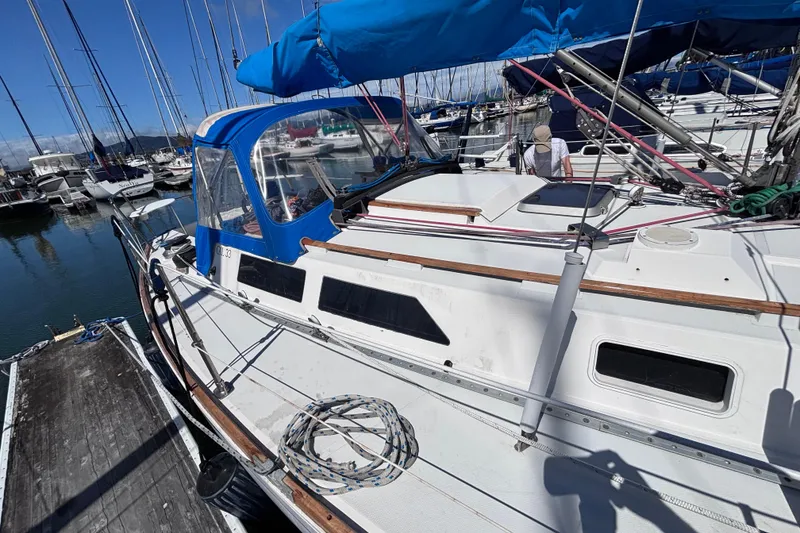 Slide: The Image of 1989 CAL 33 sailboat docked at marina with blue canopy and rigging. - 7