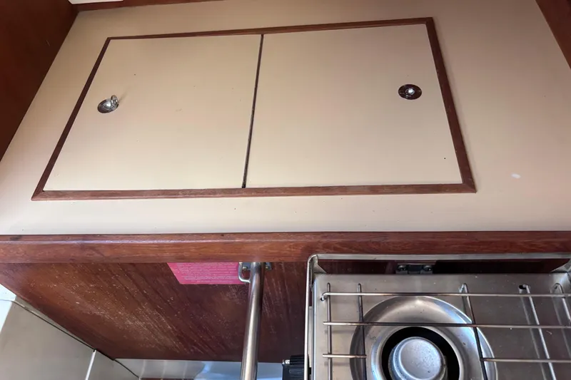 Slide: The Image of Compact kitchen area in a 1989 CAL 33 sailboat, featuring a stove and storage cabinets. - 31